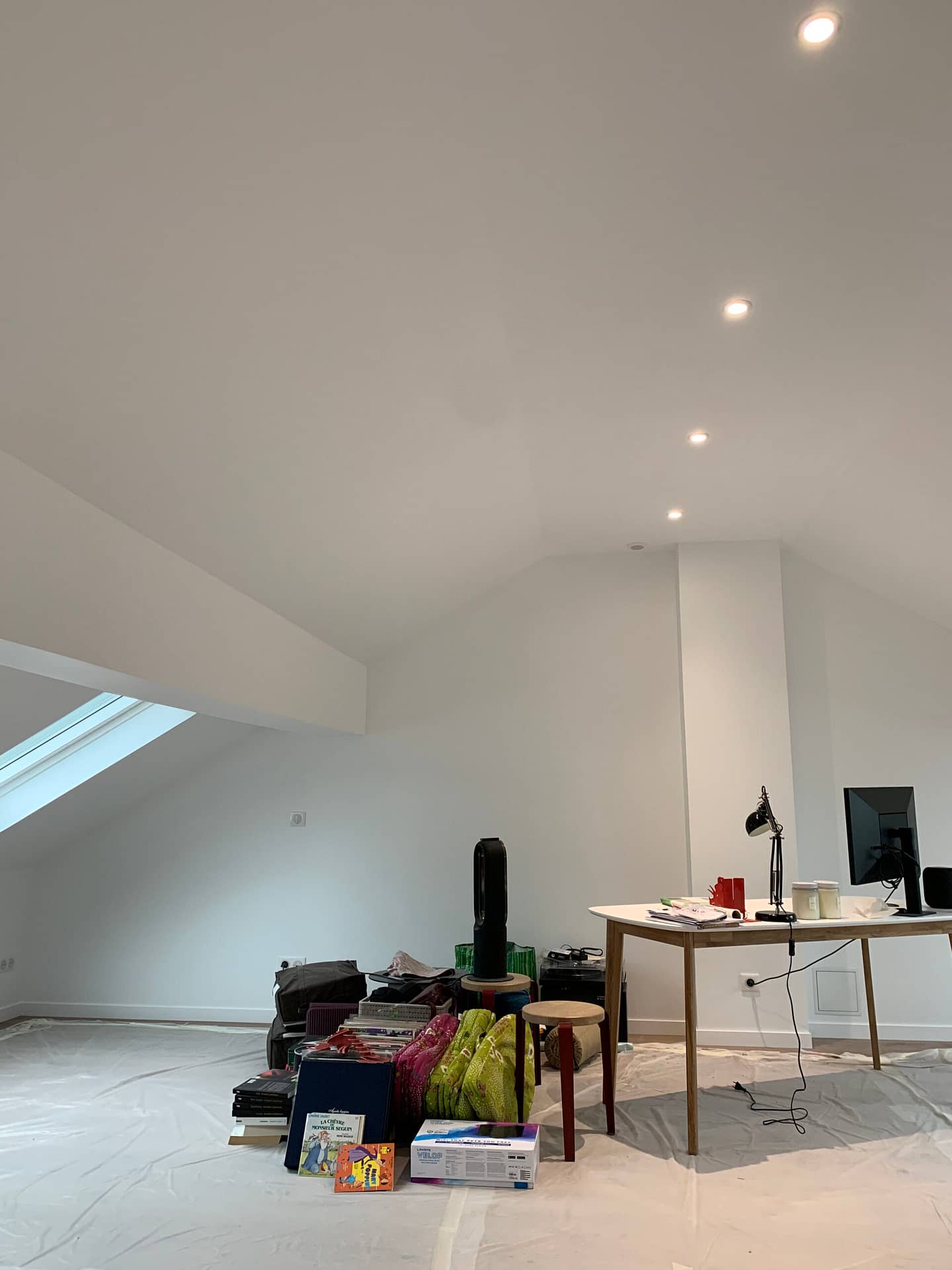 Combles en cours d'aménagement avec fenêtre de toit, éclairage encastré, et mobilier temporaire à Meudon, par Design & Couleurs.